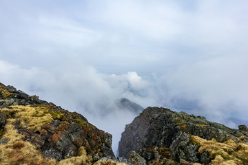 A view from a mountain summit with an other summit and altitude white clouds
