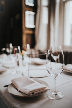 A close up shot of a restaurant table set up with tableware and wine glass. Concept of dining, hospitality and catering. Vertical image with free space for text.