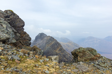 A rocky mountain view with a far away summit and altitude white clouds