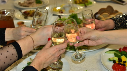 glasses of champagne in beautiful female hands during a celebration of a solemn event in a restaurant above the table