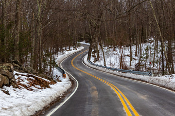 Obraz premium Acton, United States, February 27, 2019. Forest road with double yellow line in winter time, Massachusetts, United States