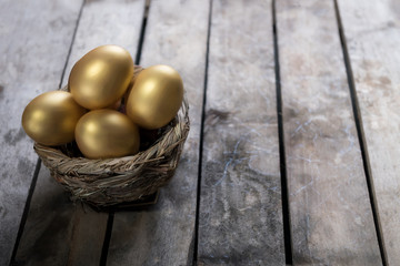 Golden eggs in nest on dark vintage wooden background