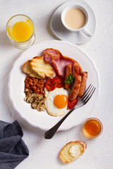 Full English or Irish breakfast with sausages, bacon, eggs, tomatoes, mushrooms and beans. Nutritious and healthy morning meal. View from above, top studio shot