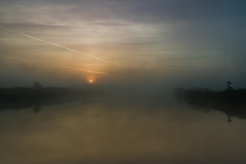 fiume  con argine all'alba con nebbia del primo mattino