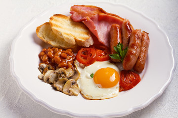 Full English or Irish breakfast with sausages, bacon, eggs, tomatoes, mushrooms and beans. Nutritious and healthy morning meal.