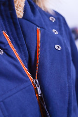 Close up of zipper on blue jacket with fur , winter fashion outfit. Jacket isolated on white background.
