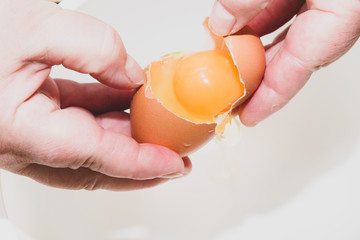Breaking a chicken egg into a white mixing bowl