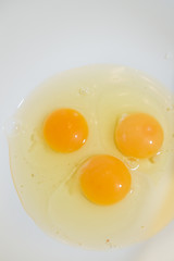 Three broken chicken eggs in a white mixing bowl