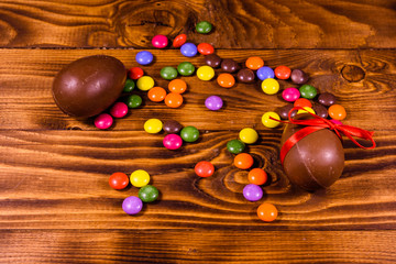 Chocolate easter eggs and multicolored candies on wooden table