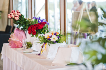 Vases with roses and wildflowers on the table in the restaurant, wedding dinner