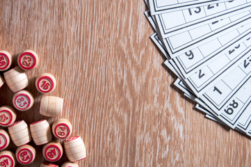 Fototapeta na wymiar Board game lotto. Wooden table. On the right, in the upper corner are the cards for the game, at the bottom left are barrels. Excitement and good luck. Group entertainment, family leisure.