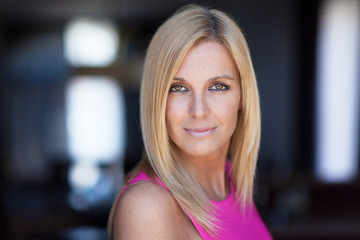 Obraz premium Portrait Of A Mature Woman Smiling At The Camera On a window background