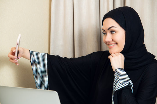 Portrait of a young attractive woman in hijab making selfie photo on smartphone.