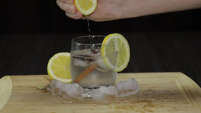 Squeezing lemon juice into a glass. Fornt view.