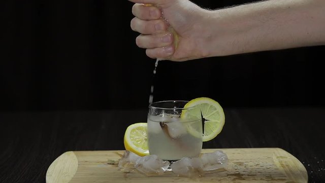 Squeezing lemon juice into a glass. Fornt view.