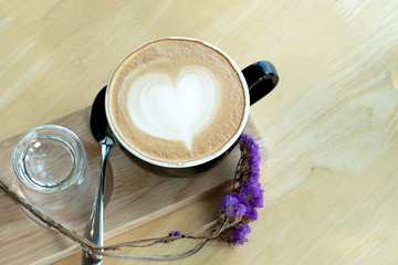 Latte art coffee in the morning time with sunlight on wooden table background at coffee shop.
