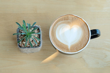 Latte art coffee in the morning time with sunlight on wooden table background at coffee shop.