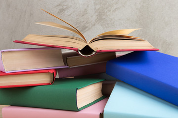 Naklejka premium Education and reading concept - group of colorful books on the wooden table, concrete wall blackboard