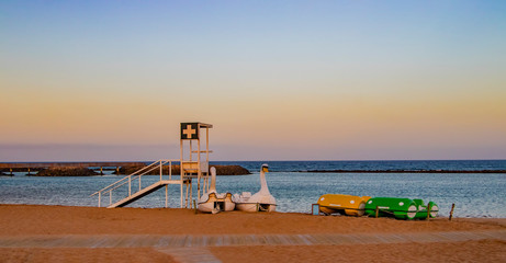 Fototapeta premium Coastguard station and pedal boats on the beach with red.