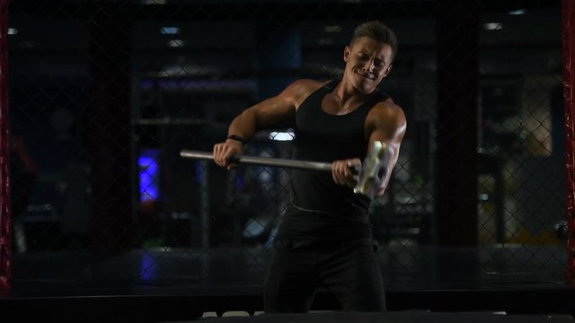 Sport muscular fitness man hitting wheel tire with hammer sledge in gym strong man fitness and bodybuilding training workout fitness concept 