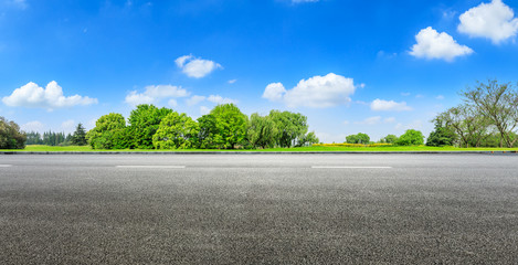 Fototapeta premium Asphalt road and green forest under blue sky