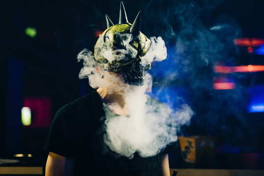 man in a mask smokes a hookah and lets a cloud of smoke