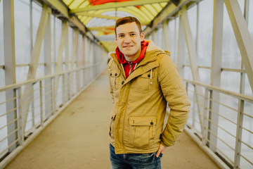 Young man on a bridge in a big city is looking into the distance