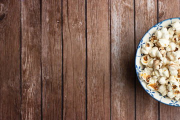 Obraz na płótnie Canvas Salt popcorn on the wooden table. Popcorn in a wooden bowl.