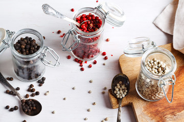 Pink, white and black peppers in a glass jars