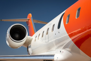 A white and orange private jet airplane against a blue sky