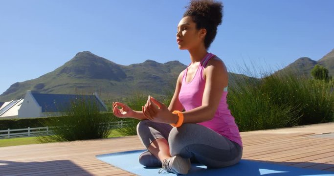Front view of young pretty mixed-race woman doing yoga in backyard of home 4k