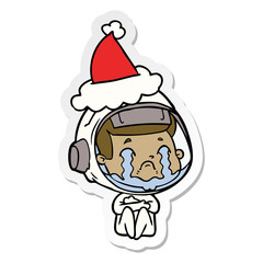 sticker cartoon of a crying astronaut wearing santa hat