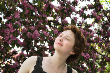 young woman squinting from allergies in a blooming garden