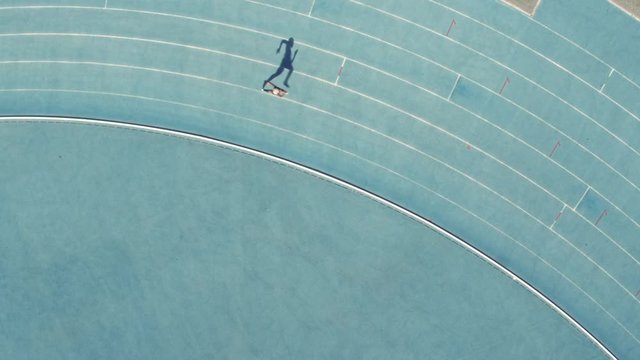 Aerial view of female runner practicing on all weather race track in stadium. Sports woman training athletics running race track.