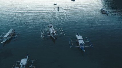 Aerial drone view of boats anchored in the bay with clear and turquoise water on the sunset. Boat and yacht in the tropical lagoon. Tropical landscape. El Nido, Palawan island, Philippines.