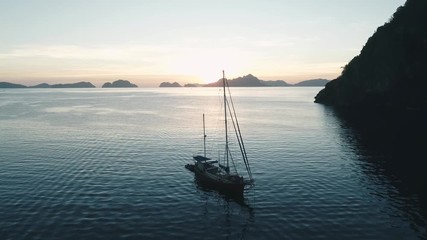 Aerial drone view of boats anchored in the bay with clear and turquoise water on the sunset. Boat and yacht in the tropical lagoon. Tropical landscape. El Nido, Palawan island, Philippines.