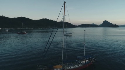 Aerial drone view of boats anchored in the bay with clear and turquoise water on the sunset. Boat and yacht in the tropical lagoon. Tropical landscape. El Nido, Palawan island, Philippines.