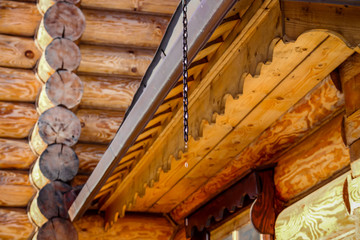 Fototapeta premium Wooden architecture and water dripping from the roof, thaw