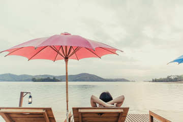 Asian woman rest on the beach in the resort admire the beauty of the lake.
