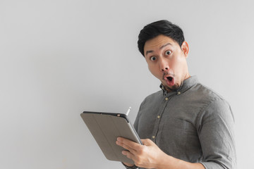 Wow and surprised entrepreneur businessman work on his tablet with grey background.