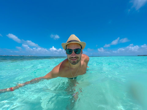 Hispanic young man taking a selfie picture in a tropical beach at San Andres, Colombia