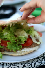 Burger in a flatbread bun with meat, lettuce, tomatoes and mayonnaise. Selective focus.