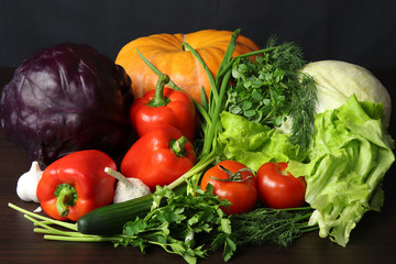 Still life of fresh vegetables. Pumpkin, white cabbage, red cabbage, two tomatoes, large and juicy red sweet peppers, greens of Basil, dill, parsley and green onions, as well as green fresh cucumber a