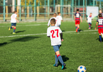 Obraz premium Football training soccer for kids. Boy runs kicks dribbles soccer balls. Young footballers dribble and kick football ball in game. Training, active lifestyle, sport, children activity concept 