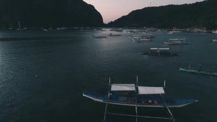 Aerial drone view of boats anchored in the bay with clear and turquoise water on the sunset. Boat and yacht in the tropical lagoon. Tropical landscape. El Nido, Palawan island, Philippines.