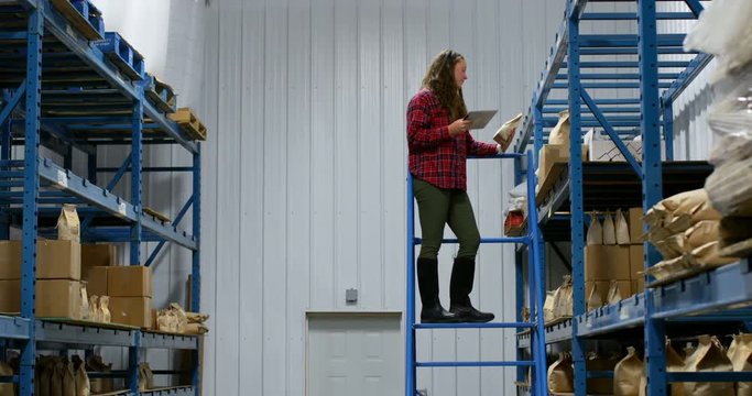 Side view of caucasian female worker checking packed goods in warehouse 4k