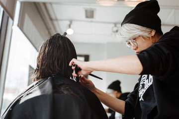 Female hairdresser cutting hair of client in salon