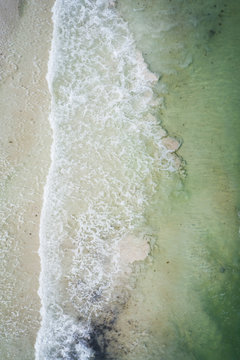 Waves crashing on beach birds eye view aerial drone