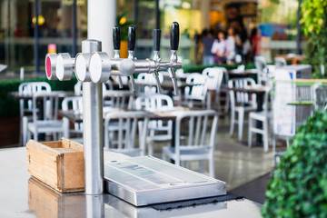 Draft beer dispenser tower 4 Tap, Outdoor close up of a row of metal spigots draft beer tap on the Bar.