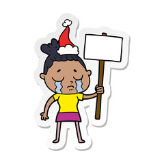 sticker cartoon of a crying woman with protest sign wearing santa hat